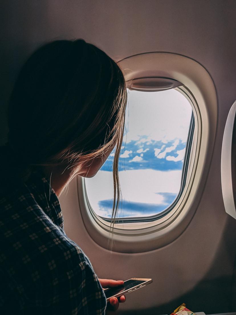 A woman looking out a plane window.